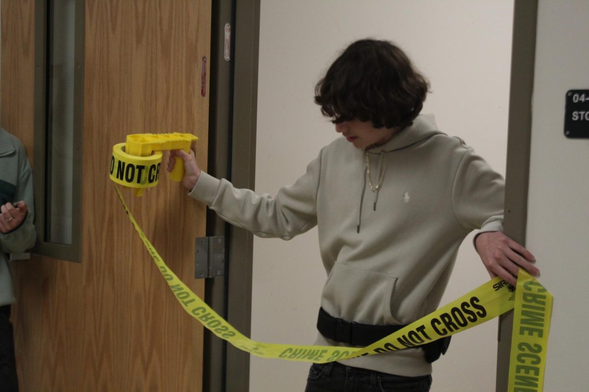 A Criminal Justice student putting up caution tape for a Crime scene. 