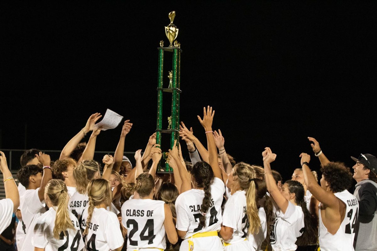 After a long night, the senior players, cheerleaders, and coaches celebrate by hoisting the Powder Puff trophy.