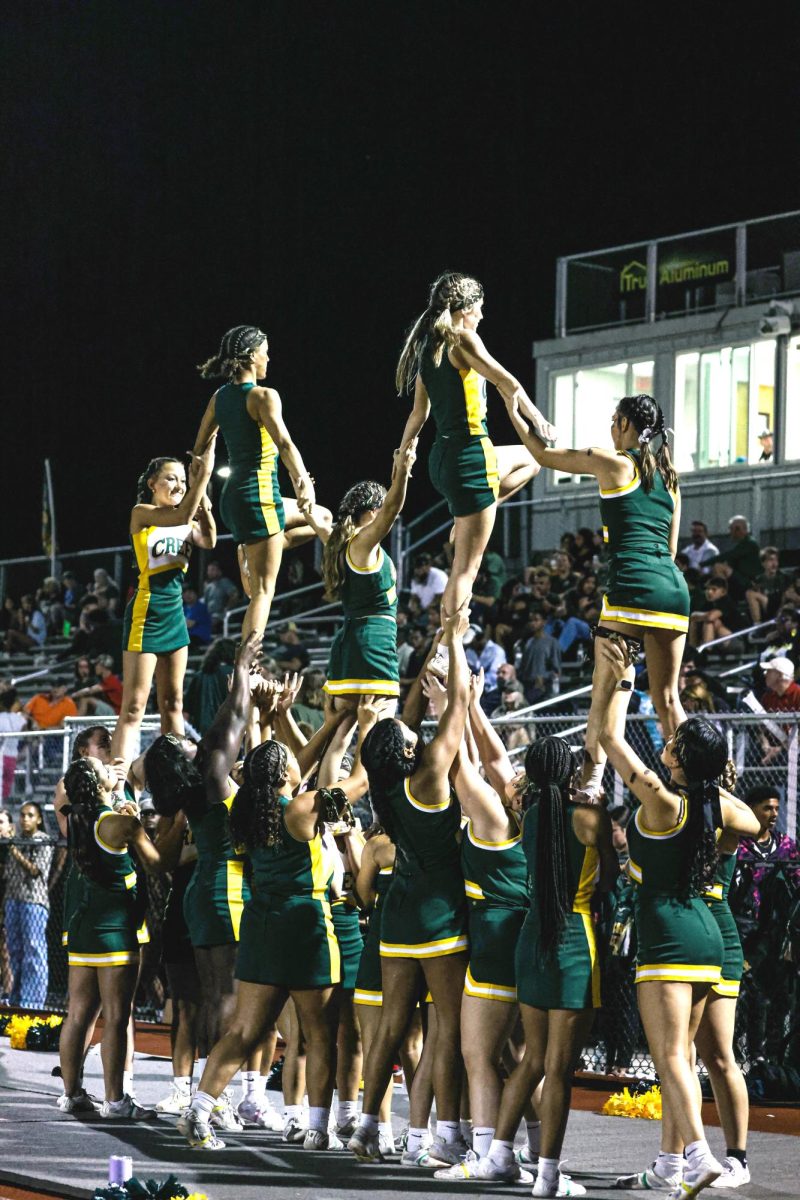 Lifting each other and the crowd. At a recent home football game, the cheer team demonstrated their skills by creating a multitier stunt. Shortly after the stunt the cheer team flawlessly finalized the dismount. 