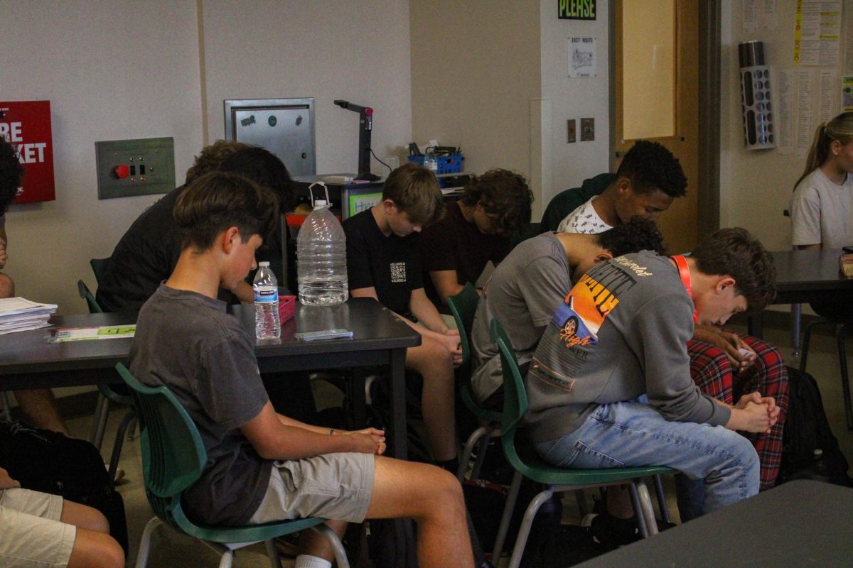 Deep in prayer. Students bowing their heads and closing their eyes as they pray along. It was the meeting’s opening prayer, asking God to have a good meeting. "quote,” said freshman Santiago Colmenares. 