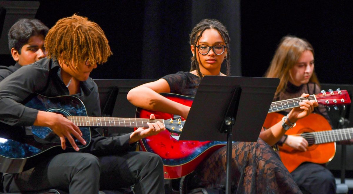 Vibrancy within music. Juniors Marcus Mitchell and Alyssa Fougere play their fall concert music at it’s respective showcase, displaying their talents through their electric blue and striking red guitars. Students were instructed to wear formal black at the concert, but their guitars did not have a dress code- as they were all personal ones, brought in by the performers. “We have a pretty small class for intermediate guitar, but everyone is close,” said junior guitarist Chase Copenhaver. 